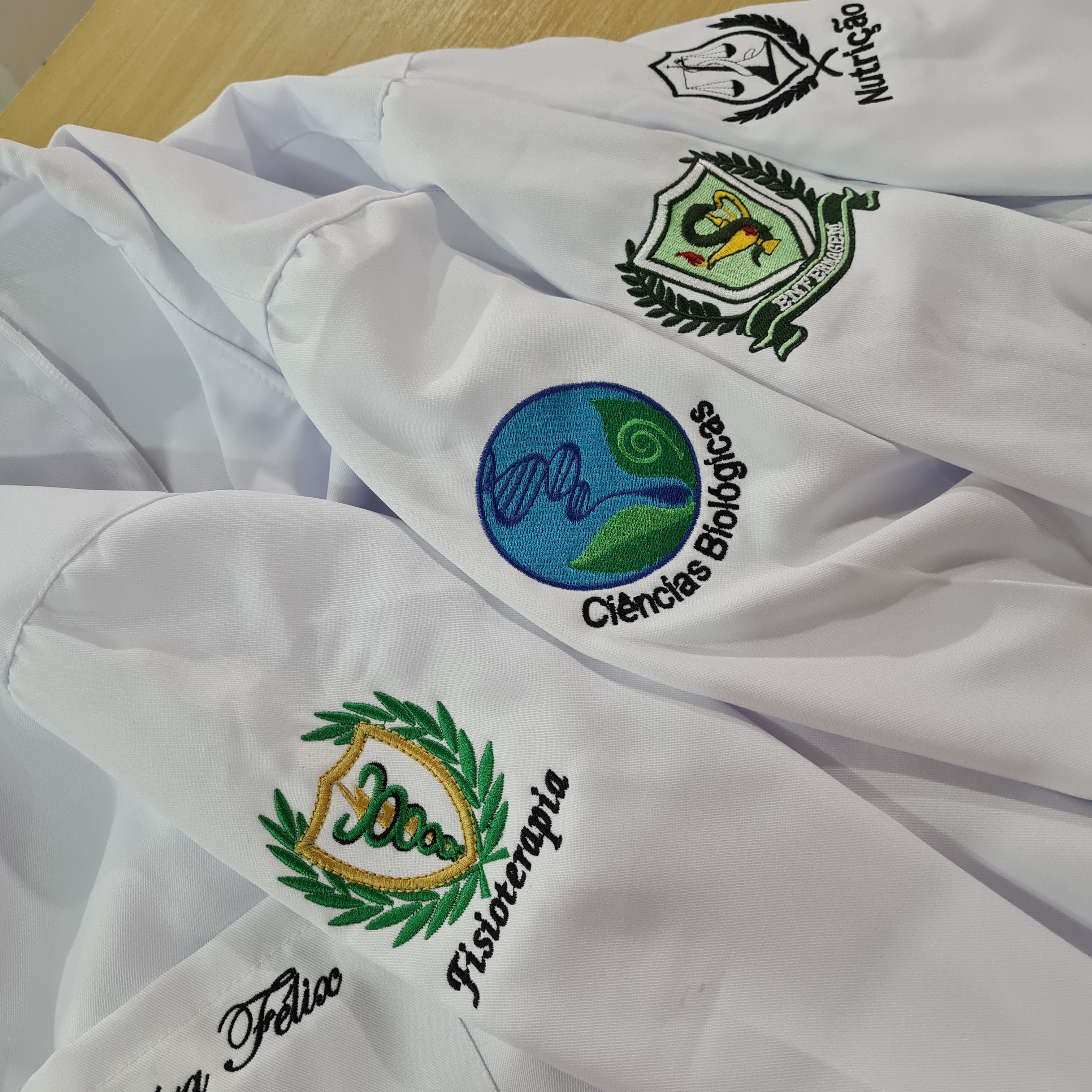 Símbolos de faculdades bordados em jalecos brancos